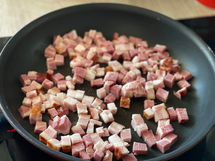 bacon-cuburi-la-prajit Cubulețe de bacon în tigaie, în timpul prăjirii, eliberând grăsime și arome intense