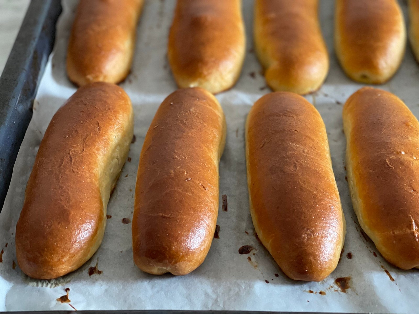 Chifle de hot dog proaspăt scoase din cuptor, coapte uniform, cu crustă aurie și lucioasănn