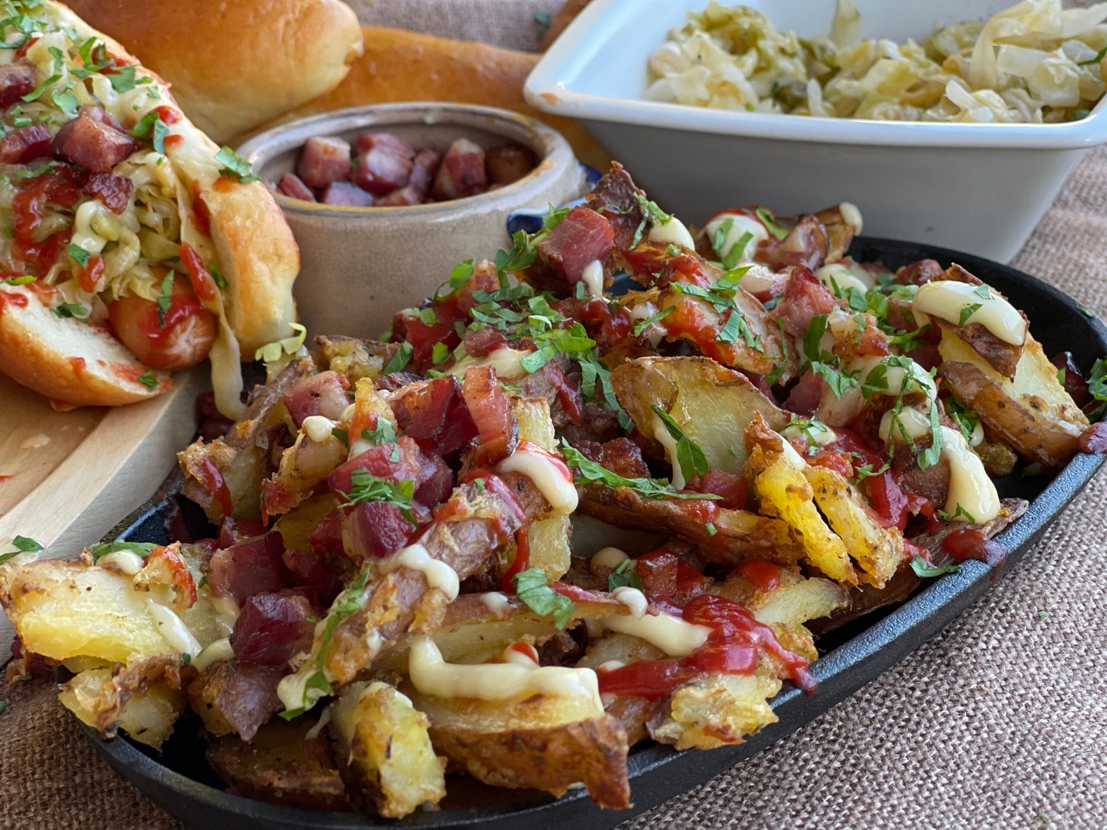 Cartofi copți acoperiți cu bacon crocant, ceapă caramelizată și sosuri de maioneză și ketchup, pregătiți pentru servire