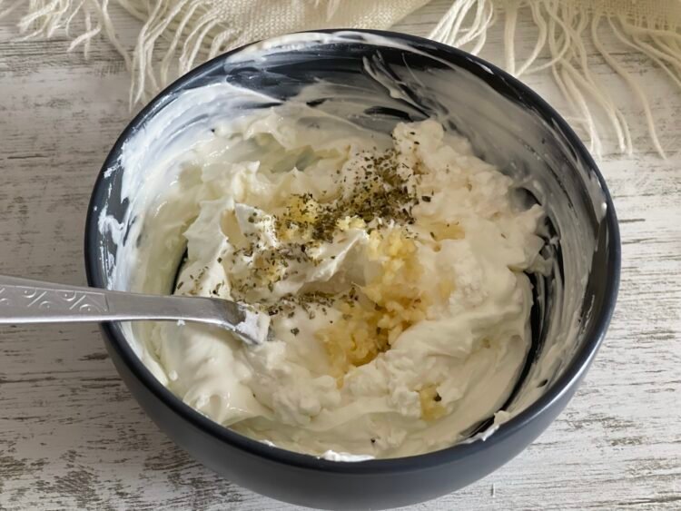 crema-branza-usturoi-oregano-galette Bol cu cremă de brânză amestecată cu usturoi zdrobit și oregano, pregătită pentru umplutura galettei.