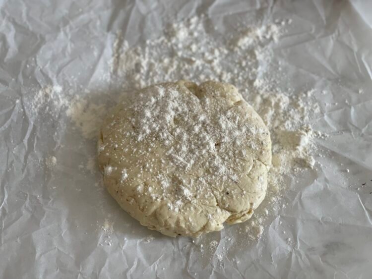 aluat-galette-inainte-intindere Bilă de aluat pe hârtie de copt, presărată ușor cu făină, pregătită pentru a fi întinsă în vederea pregătirii unei galette rustice.