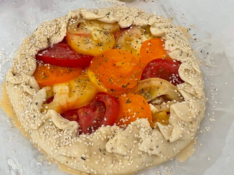 galette-unsa-ou-susan-inainte-coacere Galette formată, cu marginile împăturite, unsă cu ou și decorată cu semințe de susan, pe hârtie de copt, înainte de coacere.